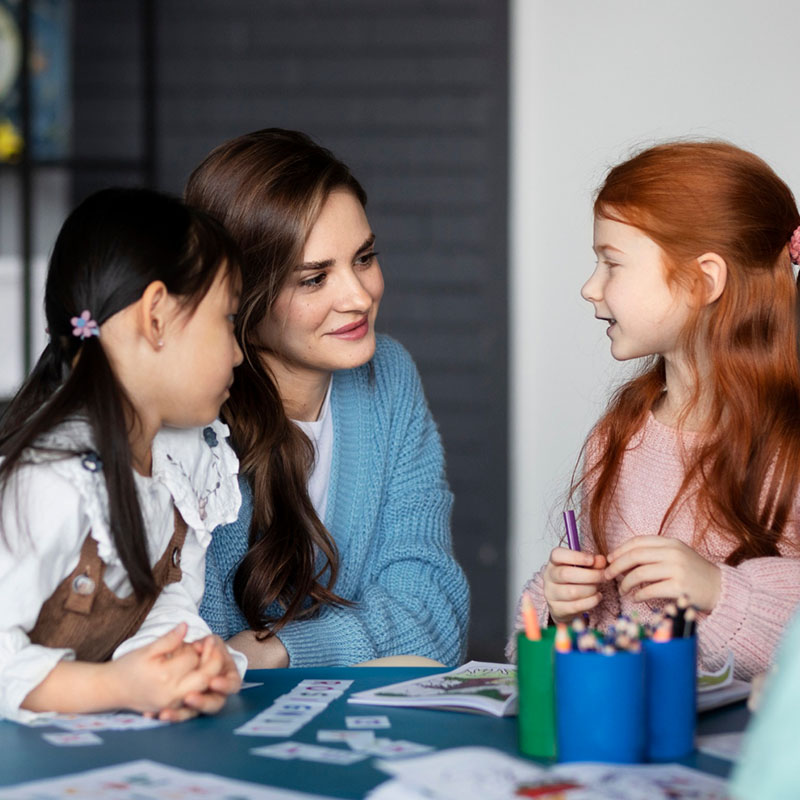 Daycare_0005_medium-shot-kids-sitting-table-with-teacher